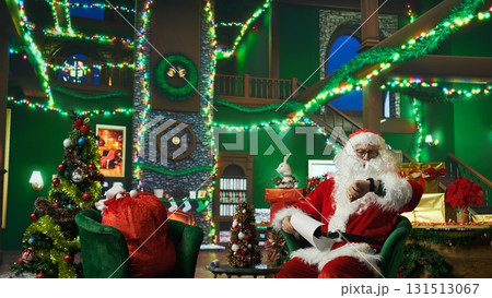 Person in Christmas costume alerted after dozing off and running late on delivering gifts to children. Santa Claus waking up after falling asleep on armchair while reading letters from kids, camera A Person in Christmas costume alerted after dozing off and running late on delivering gifts to children. Santa Claus waking up after falling asleep on armchair while reading letters from kids, camera A 131513067