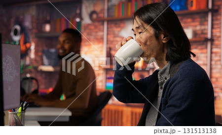 AI startup office chief technology officer drinking coffee and building application. Senior manager enjoying hot beverage while working in artificial intelligence software development agency, camera B 131513138