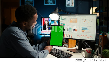 Young guy examining funds for a program and holding tablet with mockup, studying finances and accounting management on a software. Male specialist doing remote work for a startup. Camera A. 131513175