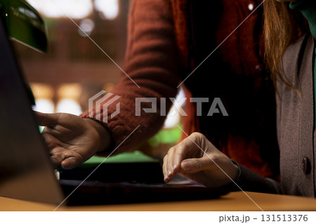 Team of diverse classmates working together on a school project at the library, meeting to compare notes and information on laptop. Preparing for research within the academic archived files. Team of diverse classmates working together on a school project at the library, meeting to compare notes and information on laptop. Preparing for research within the academic archived files. 131513376