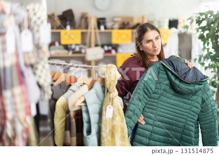 During November sales, Latin woman choose down coat, other client in background During November sales, Latin woman choose down coat, other client in background 131514875