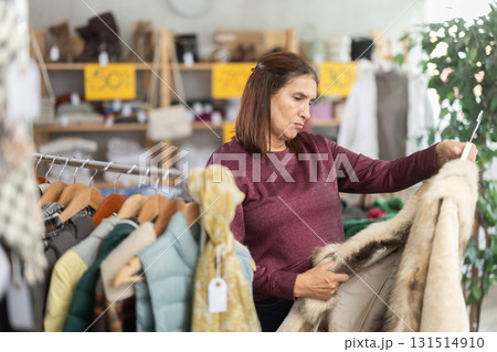 Female shopper chooses beautiful fur coat in clothing store Female shopper chooses beautiful fur coat in clothing store 131514910