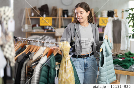 During November sales, young woman choose and buy something autumn outwear During November sales, young woman choose and buy something autumn outwear 131514926