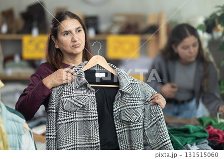 Adult woman chooses jacket in clothing store 131515060