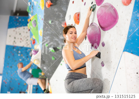 Young woman practicing rock climbing on climbing wall 131515125