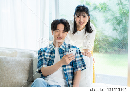 リビングでスマホを見るカップル リビングでスマホを見るカップル 131515142
