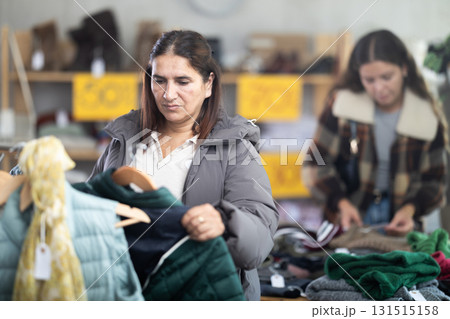 Adult woman choosing down coat in clothing store 131515158