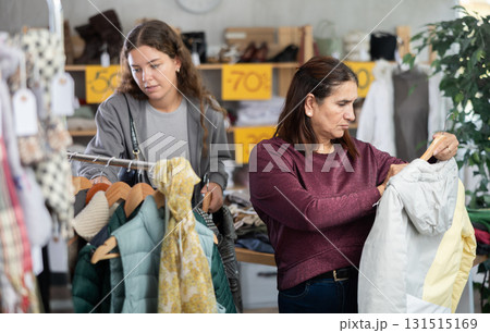 During November sales, Latin woman choose down coat, other client in background During November sales, Latin woman choose down coat, other client in background 131515169