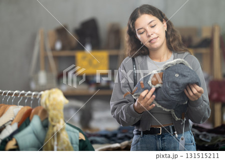 Young woman choosing fur hat in clothing store Young woman choosing fur hat in clothing store 131515211