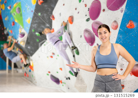 Cheerful sporty young girl inviting to workout in climbing center Cheerful sporty young girl inviting to workout in climbing center 131515269