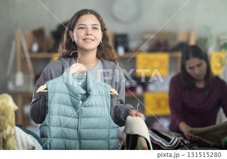 During November sales, young woman choose vest, other client in background During November sales, young woman choose vest, other client in background 131515280