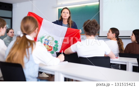 Adult female teacher showing flag of Peru to students 131515421