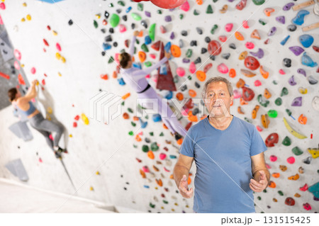 Friendly senior advanced climbing coach showing bouldering wall Friendly senior advanced climbing coach showing bouldering wall 131515425
