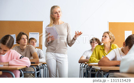 Classmates and female teacher working in groups to complete task during class Classmates and female teacher working in groups to complete task during class 131515429