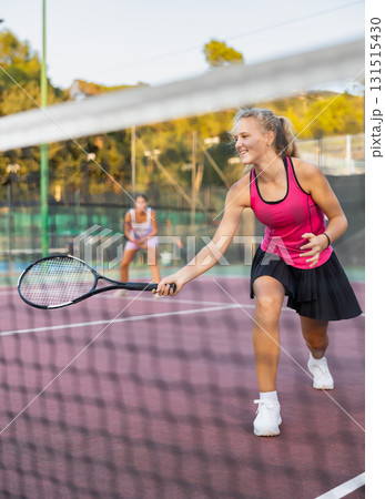 Young woman in skirt playing tennis on court 131515430