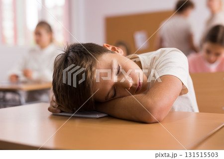 Tired boy sleeping at desk in classroom Tired boy sleeping at desk in classroom 131515503