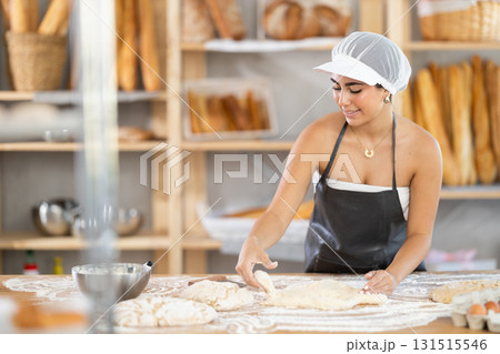 Young woman baker kneads the dough in bakery Young woman baker kneads the dough in bakery 131515546