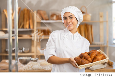 Young female baker with basket of croissants 131515553