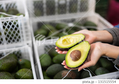 Fresh ripe sliced avocado on hand, blurred boxes with fruits 131515554