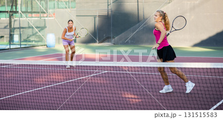 Girl playing tennis ball friendly match on outdoors court 131515583
