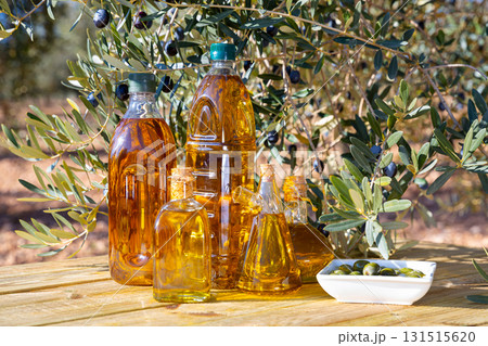Bottles with olive oil and olive branch on a wooden table Bottles with olive oil and olive branch on a wooden table 131515620