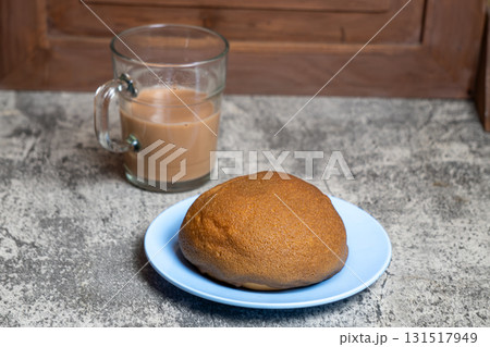 Deliciously baked coffee bun alongside a warm drink, perfect for a cozy morning or afternoon treat. 131517949