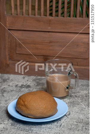 Deliciously baked coffee bun alongside a warm drink, perfect for a cozy morning or afternoon treat. 131517950