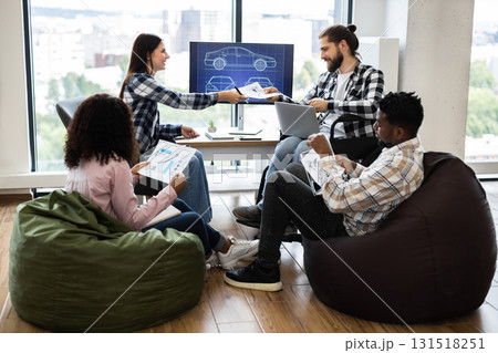 Group of young adults collaborating on vehicle design tasks in open office. Various ethnicities and genders working together, focusing on creativity and teamwork. Group of young adults collaborating on vehicle design tasks in open office. Various ethnicities and genders working together, focusing on creativity and teamwork. 131518251
