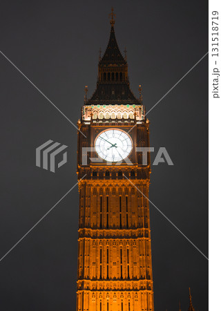 Nighttime view of Elizabeth Tower, also known as Big Ben, in London. The clock face glows brightly, highlighting the tower's intricate architecture. 131518719
