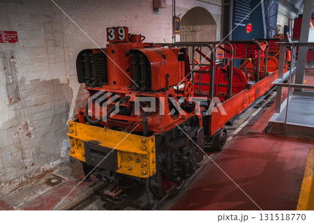 A red and yellow industrial locomotive with number 39 on tracks indoors, set against brick walls and arched doorways in a historical museum setting. 131518770