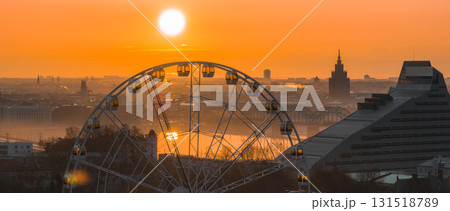 A sunrise view of Riga, Latvia, featuring a Ferris wheel, the National Library, the Latvian Academy of Sciences spire, and bridges over the Daugava River. A sunrise view of Riga, Latvia, featuring a Ferris wheel, the National Library, the Latvian Academy of Sciences spire, and bridges over the Daugava River. 131518789