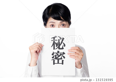 秘密と書かれた紙を両手で持ち視線を投げるシニア女性 131519395