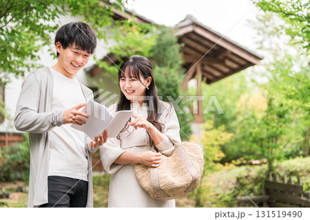 旅行先でガイドブックを見ながら行き先を探す若い夫婦・カップル 131519490