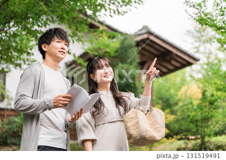 旅行先でガイドブックを見ながら行き先を探す若い夫婦・カップル 131519491