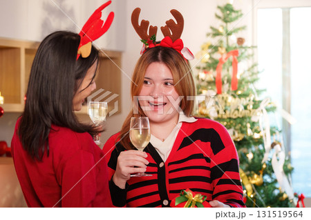 Holiday Celebration. Two friends enjoying festive drinks and exchanging gifts during Christmas party. 131519564