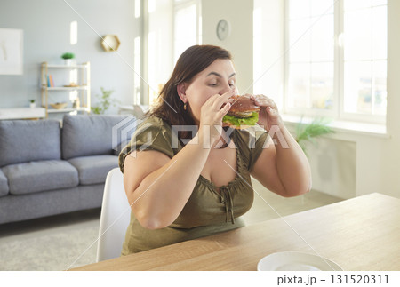 Obese hungry woman with excessive fat eating unhealthy fast food, tasty hamburger, juicy burger Obese hungry woman with excessive fat eating unhealthy fast food, tasty hamburger, juicy burger 131520311