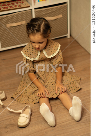 Young girl in polka dot dress preparing beige shoes Young girl in polka dot dress preparing beige shoes 131520446