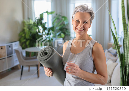 A mature woman of age with gray hair smiles and holds a glass with clean drinking water A mature woman of age with gray hair smiles and holds a glass with clean drinking water 131520820