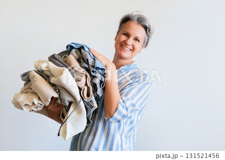 Mature gray haired woman holding stack of clothes isolated on white background 131521456