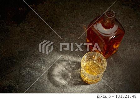 Bottle and crystal glass of whiskey on a stone table. Bottle and crystal glass of whiskey on a stone table. 131521549