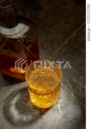 Bottle and crystal glass of whiskey on a old stone table. Bottle and crystal glass of whiskey on a old stone table. 131521550