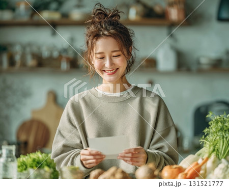 Asian woman smiling reading recipe in kitchen Asian woman smiling reading recipe in kitchen 131521777
