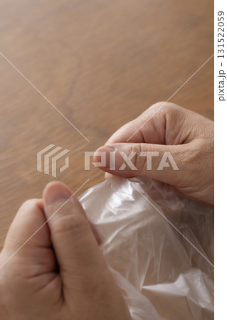 手が乾燥してビニール袋が開けられないシニア女性の手元 131522059
