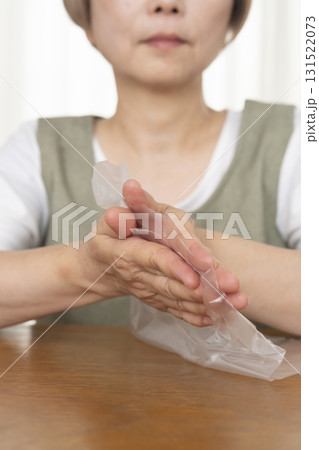 手が乾燥してビニール袋が開けられないシニア女性の手元 131522073