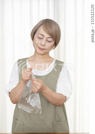 手が乾燥してビニール袋が開けられないシニア女性 131522120