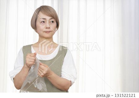 手が乾燥してビニール袋が開けられないシニア女性 手が乾燥してビニール袋が開けられないシニア女性 131522121