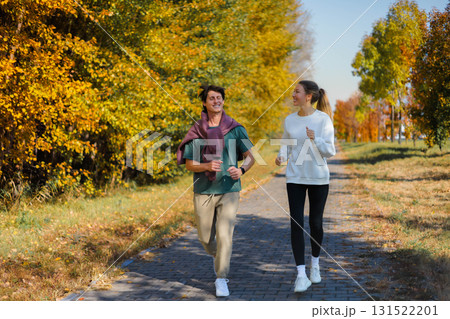 Sporty family couple morning jogging in city autumn beautiful park. Young active man Sporty family couple morning jogging in city autumn beautiful park. Young active man 131522201