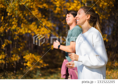 Young beautiful couple jogging in city beautiful autumn park and forest, enjoying outdoor sports 131522205