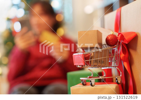 Christmas shopping cart. Mini cart with packages and smartphone in background. Christmas shopping cart. Mini cart with packages and smartphone in background. 131522619