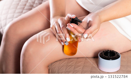 Girl holding home portable massager and anti-cellulite oil. Concept of home massage to yourself, close-up Girl holding home portable massager and anti-cellulite oil. Concept of home massage to yourself, close-up 131522784